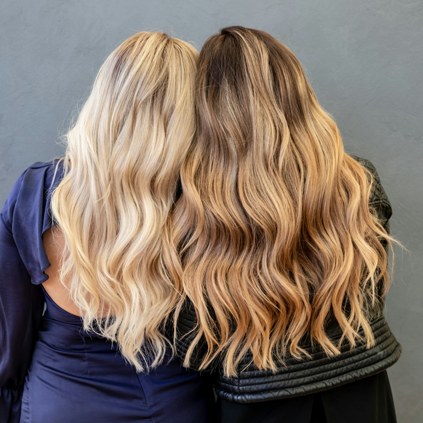Dos melenas onduladas vistas de espaldas, una rubia y otra castaña con balayage